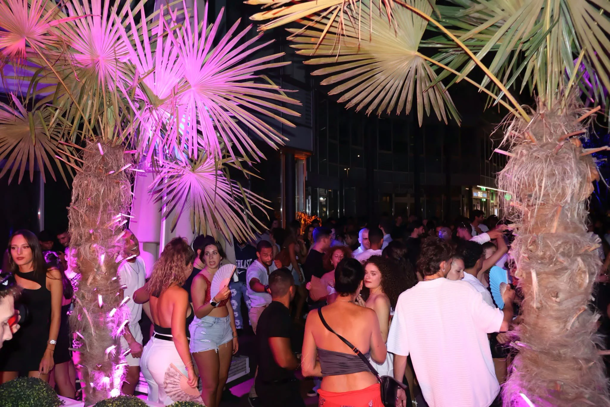 The floor at The Raum, palms lit pink over a full crowd
